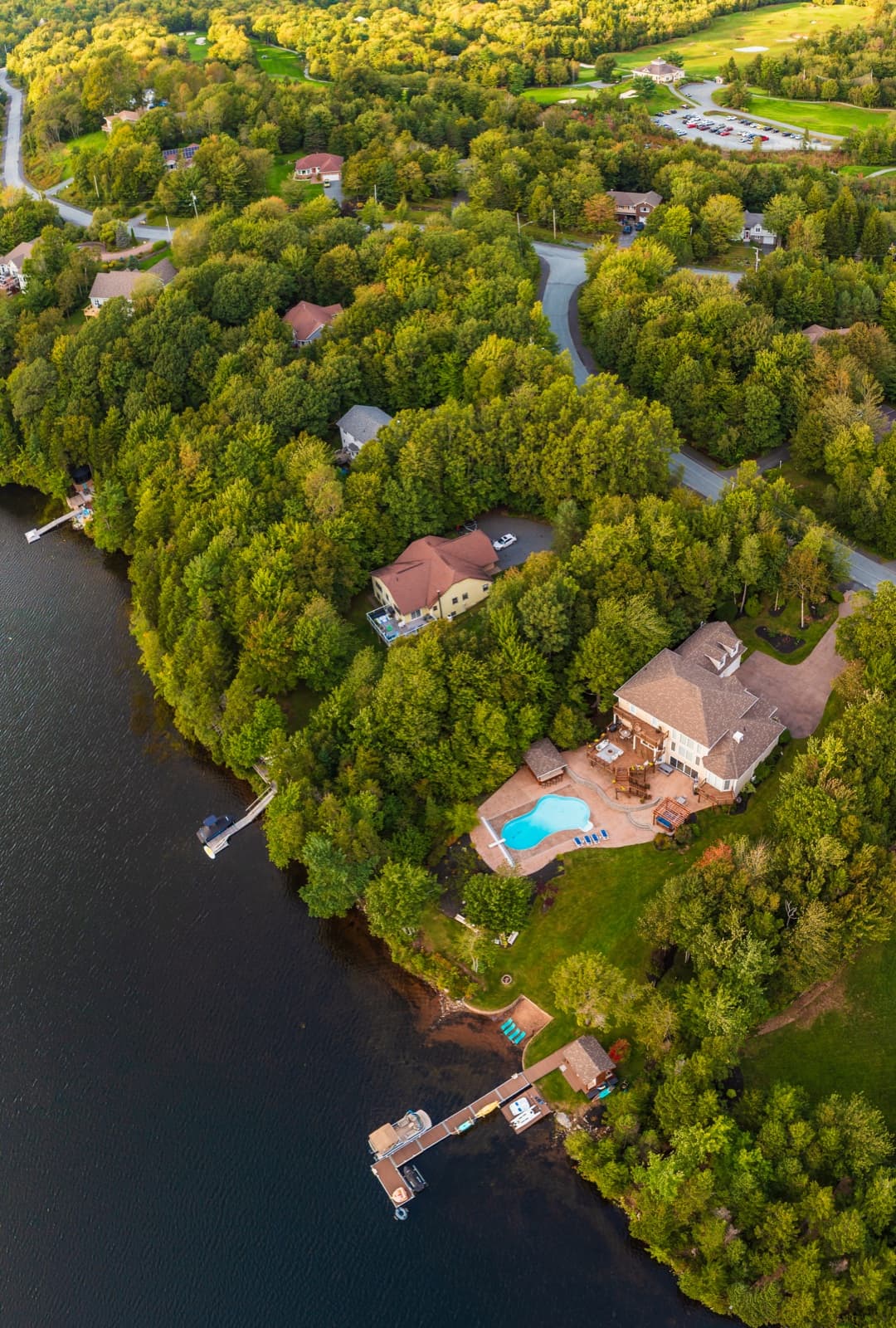 Aerial real estate photo of a lakefront property showing the house, pool and waterfront dock