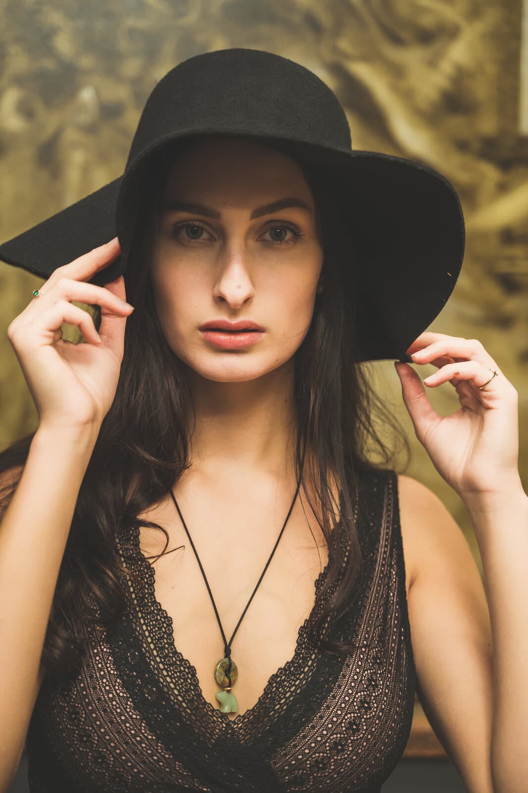 Close editorial portrait with a wide-brim hat, warm tones