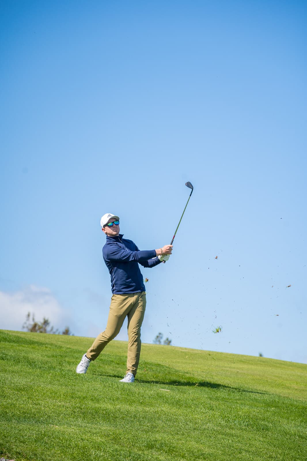 Golfer's follow-through swing against a clear sky, Northumberland Links