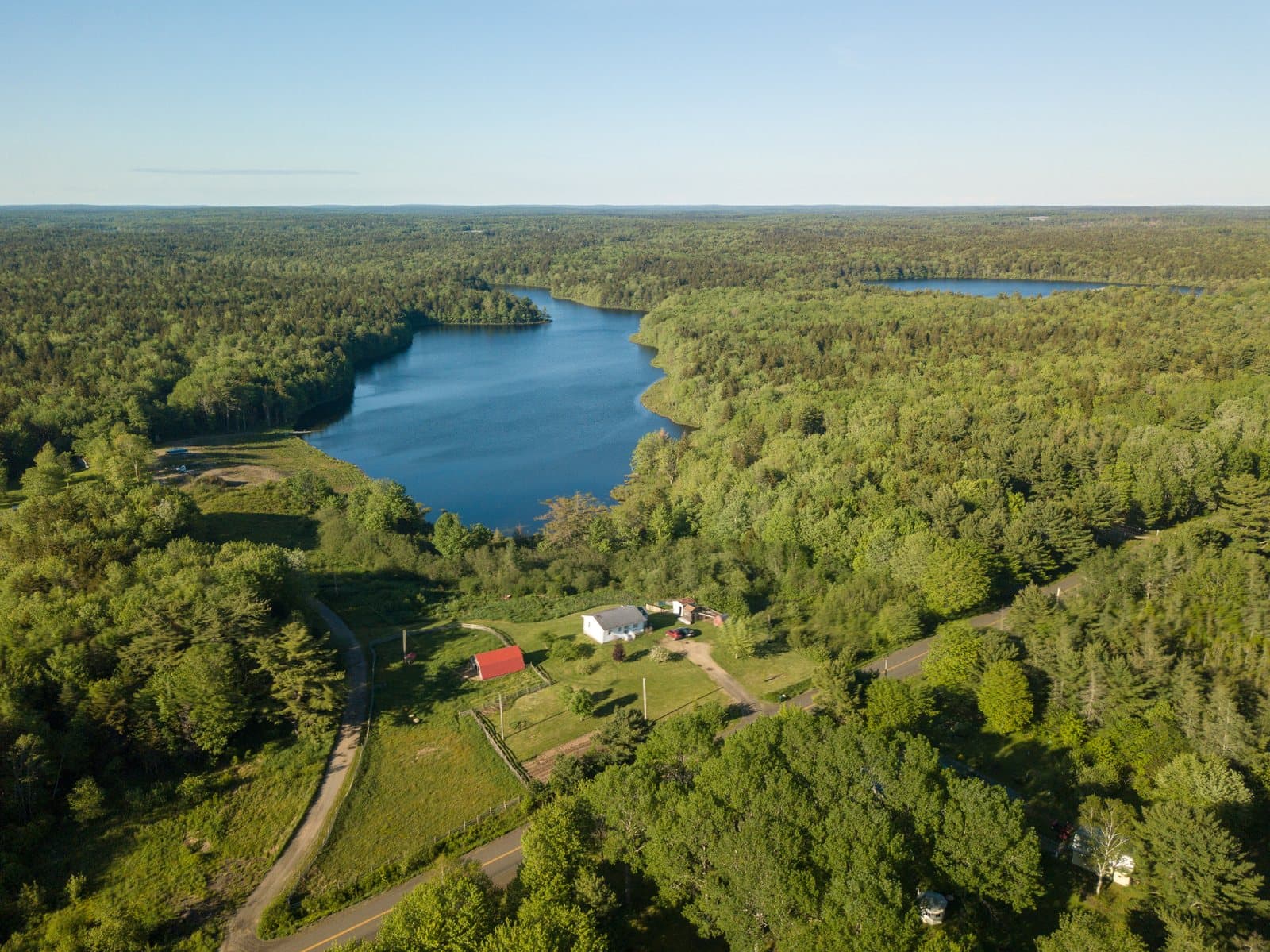 Aerial establishing shot of a lake and farmhouse near Yarmouth, Nova Scotia