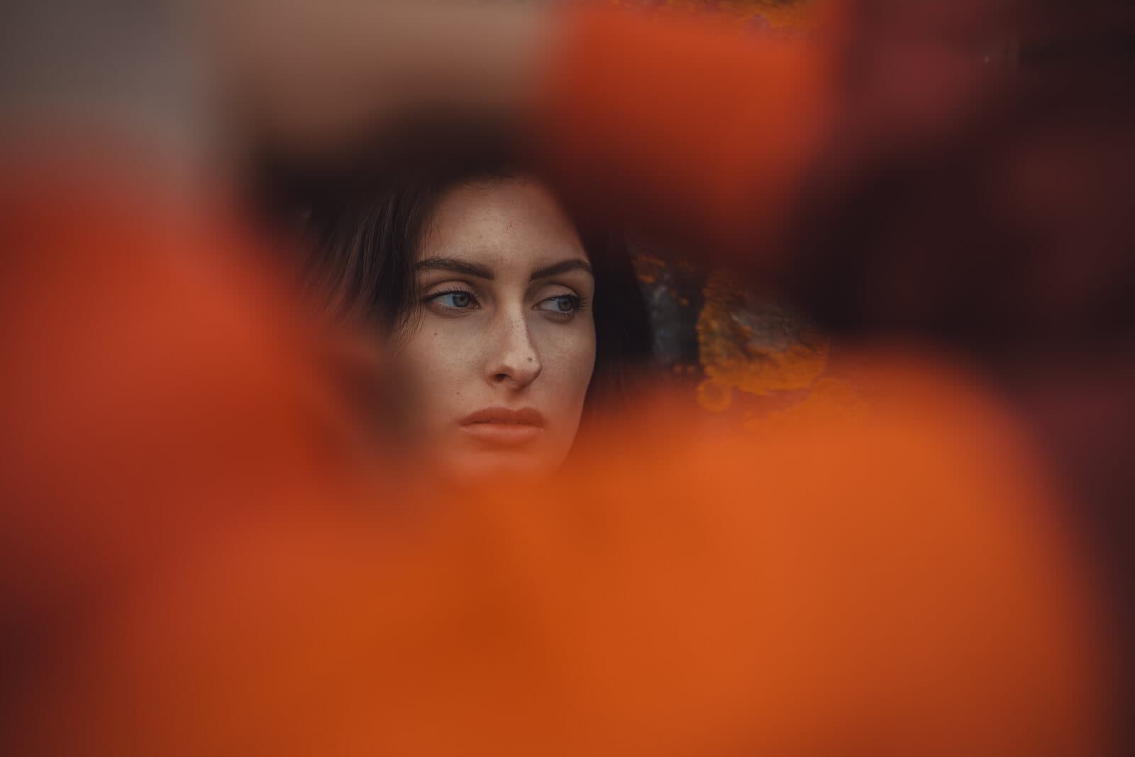 Editorial portrait shot through a soft orange-blurred foreground, dreamlike mood