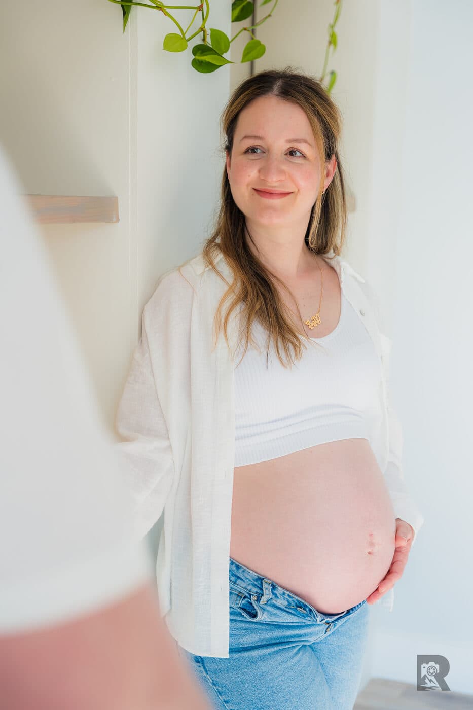 Side profile maternity portrait against a plain wall at home