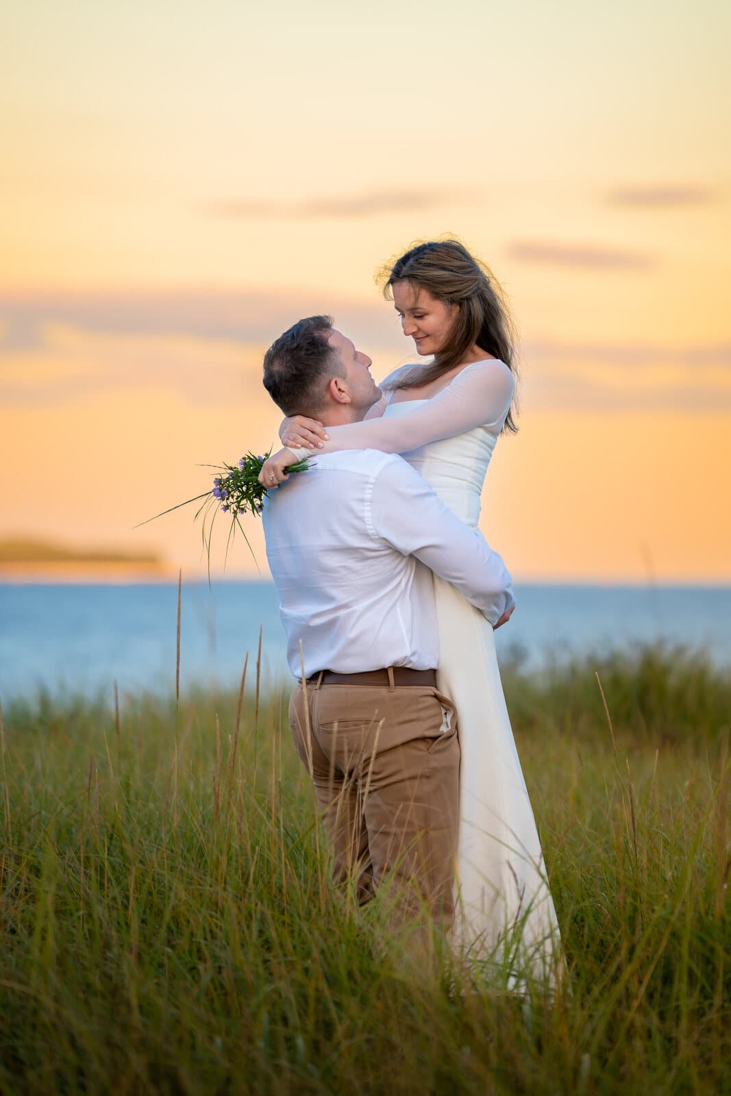Groom-to-be lifting his partner in a sunset field, Nova Scotia